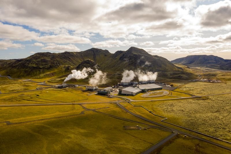 Vista aérea de una central geotérmica con vapor y montañas en Islandia