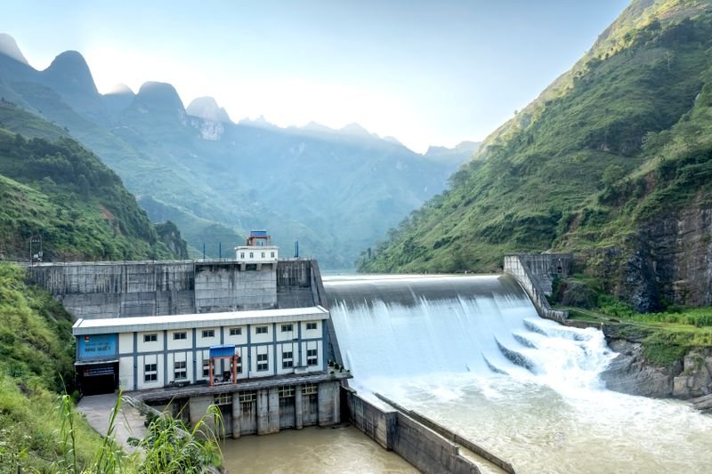 Presa hidroeléctrica con agua fluyendo frente a montañas